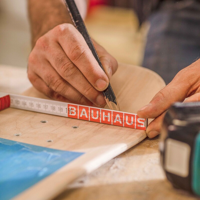 Mit Hilfe eines Bleistifts werden Löcher auf dem Skateboard angezeichnet
