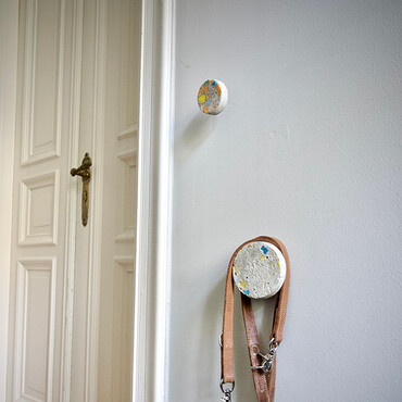 Wandhaken aus Beton hängen an einer weißen Wand neben einer Tür