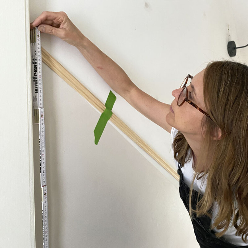 Frau misst mit Zollstock Wand aus