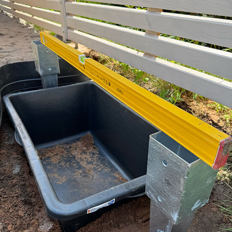 Mörtelkasten zwischen zwei Einschlaghülsen, obendrauf Wasserwaage