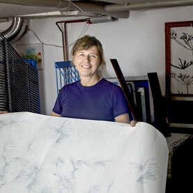 Siebdruckerin hält großes Blatt mit Mustern in der Hand
