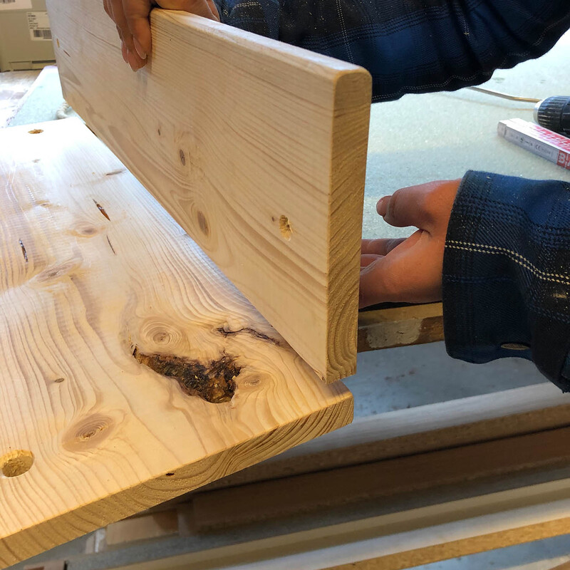 Hand hält Holzbrett: Montage einer DIY Yogamattenhalterung aus Holz
