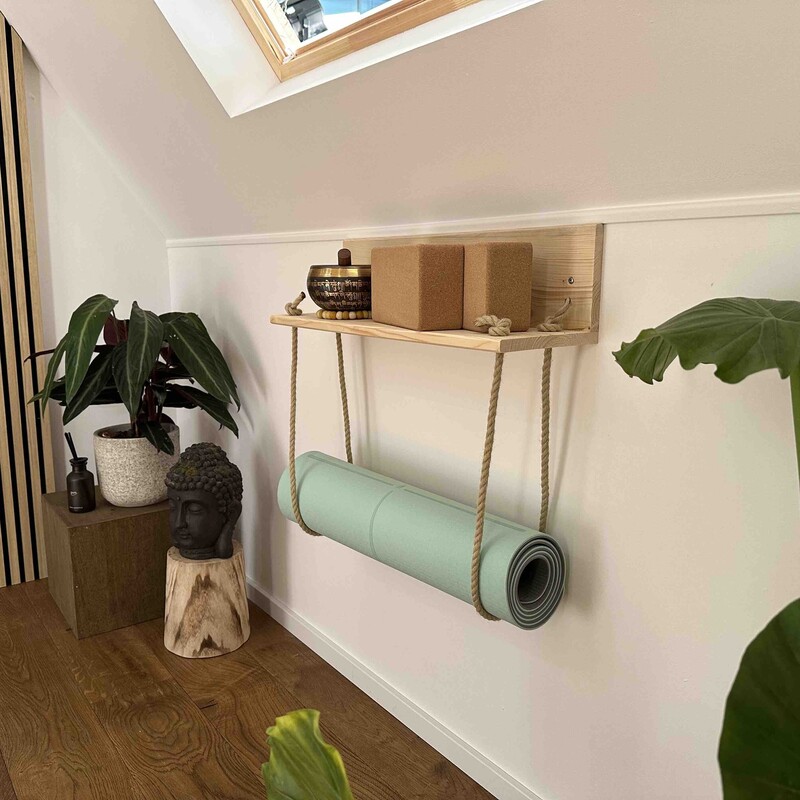 Selbstgebautes Yogamatten-Regal hängt an der Wand daneben Pflanzen