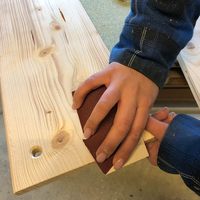 Abschleifen eines Holzbrettes mit Schleifpapier von Hand