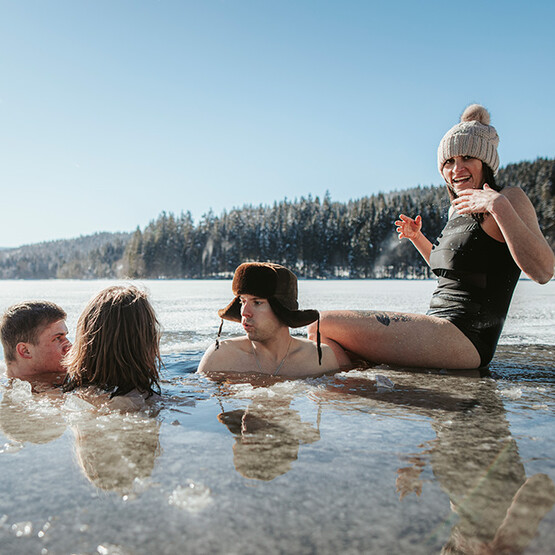 Vier Menschen baden in einem Eissee