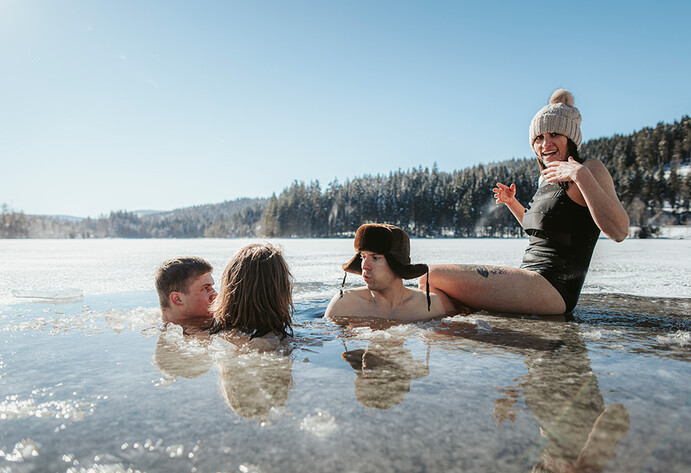 Vier Menschen baden in einem Eissee