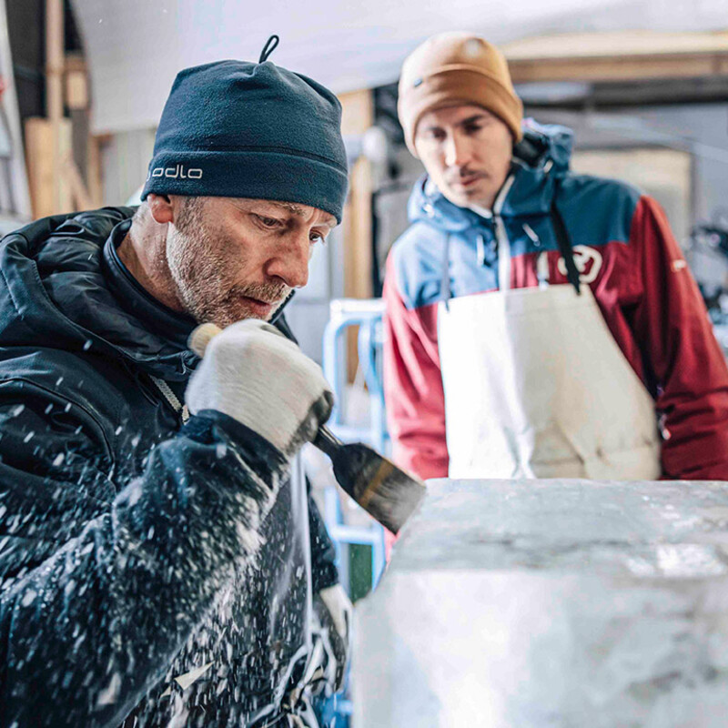 Zwei Männer, Künstler Reto Grond und Autor Alexander Zimmermann, beim Bearbeiten einer Eisskulptur