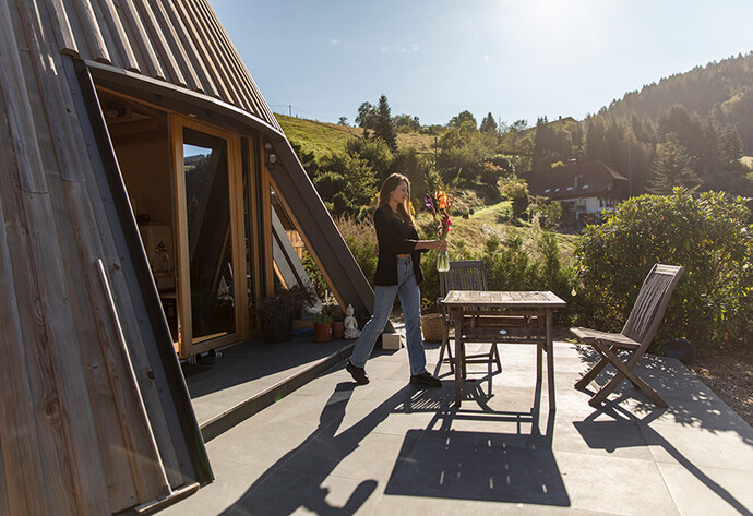 Frau h&auml;lt Blumenvase und l&auml;uft auf Terrasse