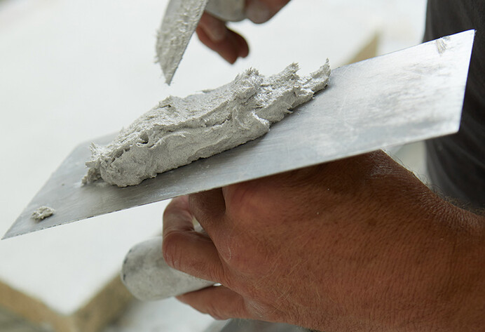 Eine Hand hält Spachtel mit Spachtelmasse in der Hand