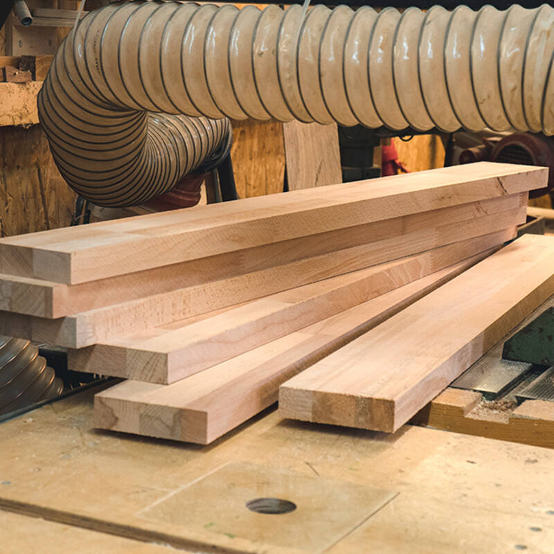 Zugeschnittene Holzleisten liegen auf einer Werkbank
