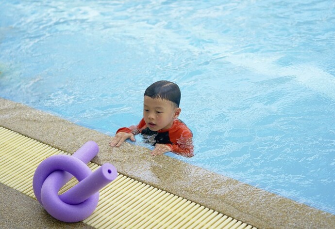 Kind übt schwimmen mit Schwimmnudel