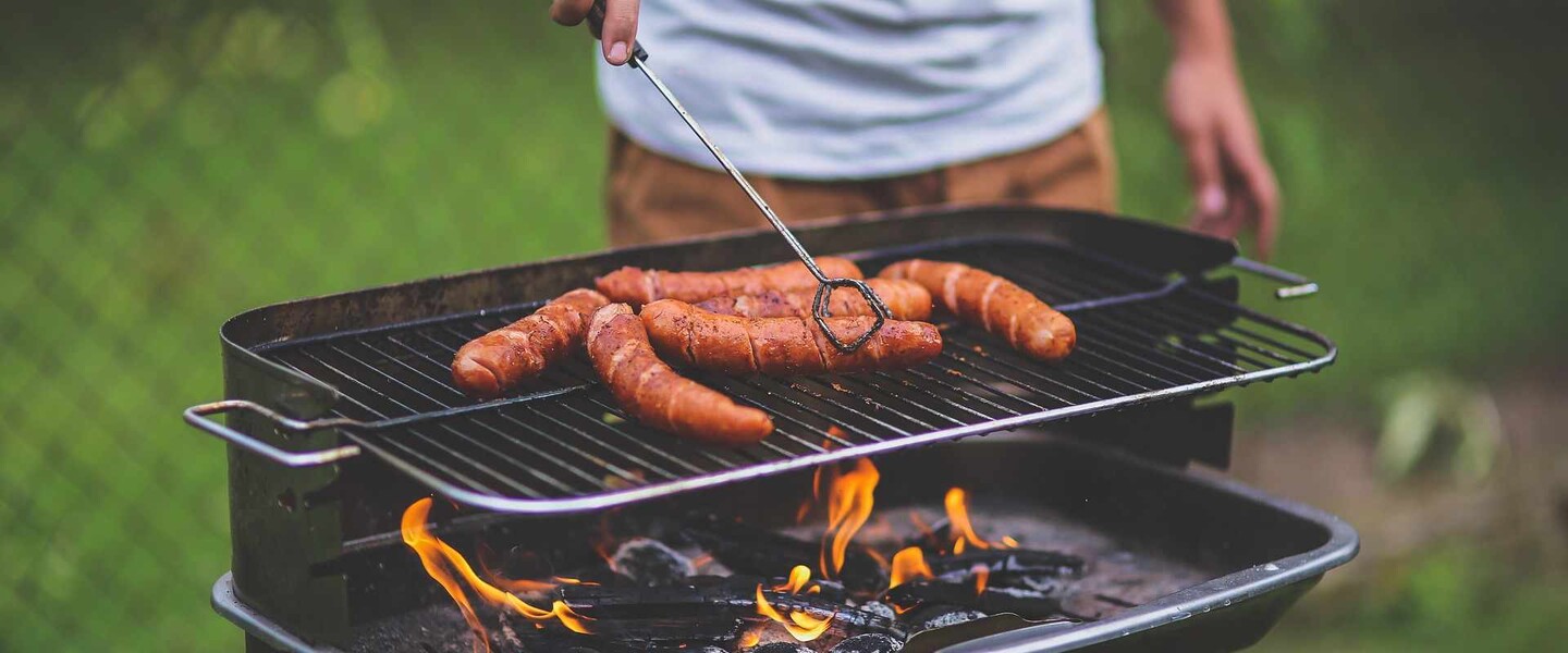 Mann grillt Würstchen