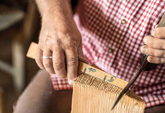Schindelmacher Ernst Karle prüft das Maß eines Holzstückes