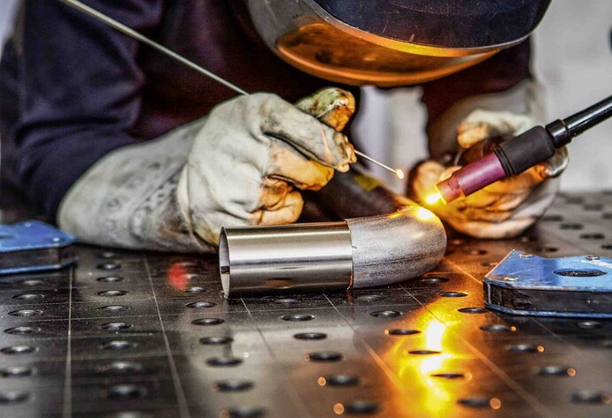 Hannah Kuhlmann mit Schwei&szlig;maske und Stahlrohr