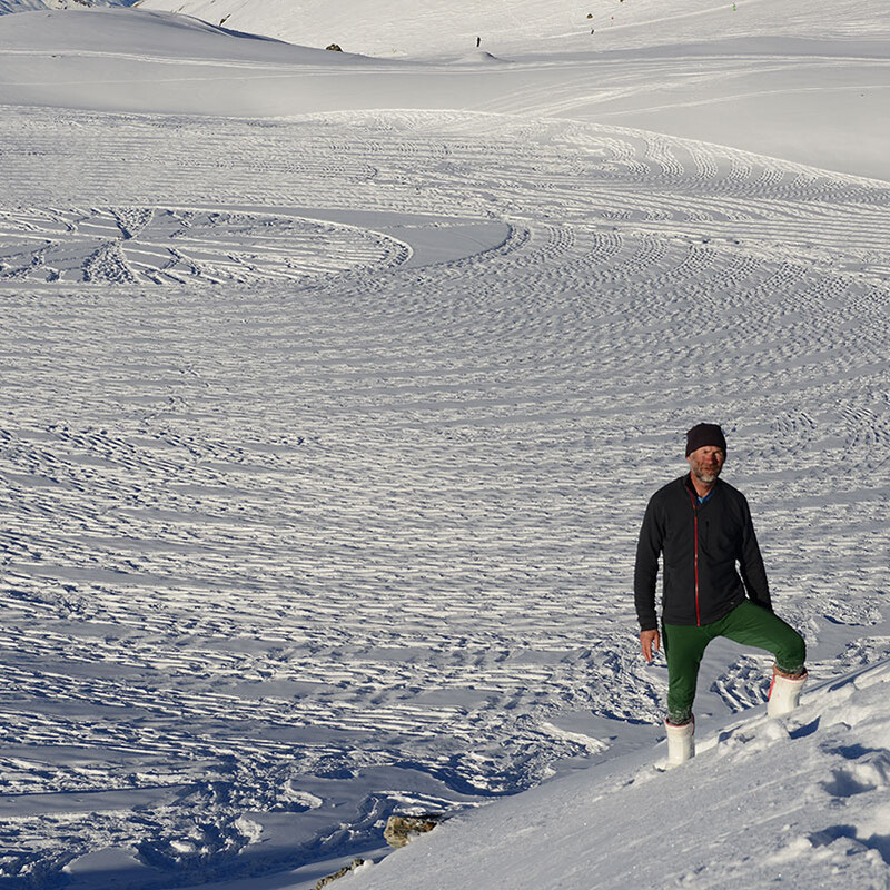 &Auml;lterer Mann mit Bart und M&uuml;tze, im Hintergrund geometrische Formen im Schnee