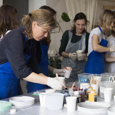 Autorin Catherine Hug und weitere Kursteilnehmer stehen im Atelier und experimentieren mit verschiedenen Farben