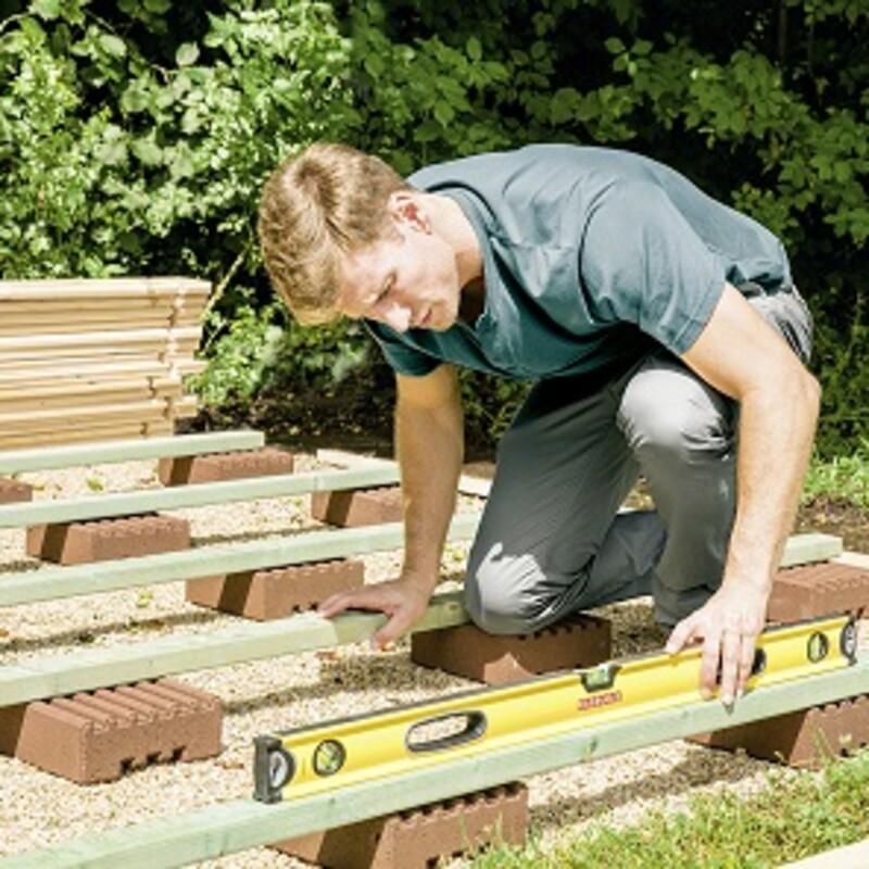 Mann legt Wasserwaage auf, um Fundament auszurichten