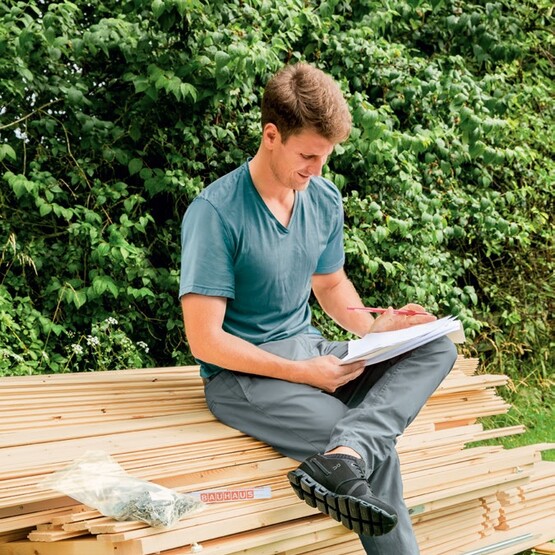 Mann studiert Aufbauanleitung für ein Gartenhaus