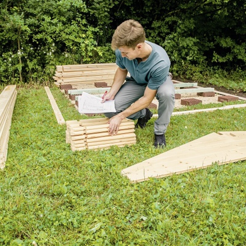 Mann prüft, ob das Material des Blockbohlenhauses komplett ist