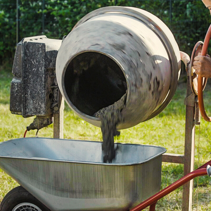 Beton aus Mischmaschine in Schubkarre füllen