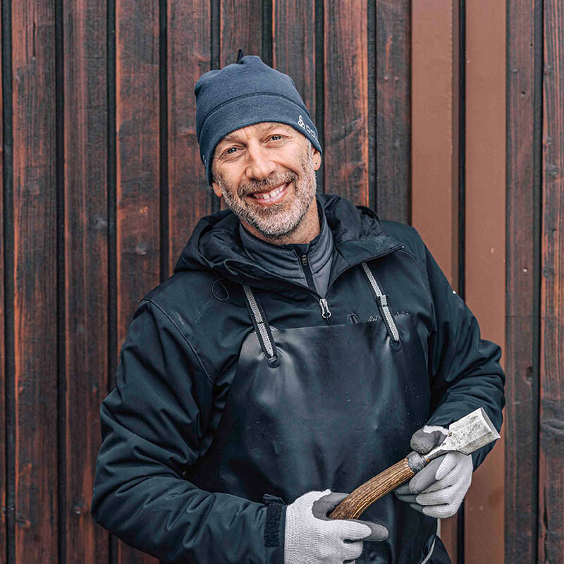 Reto Grond mit Stechbeitel in der Hand vor Holzwand