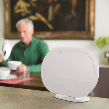 &Auml;lteres Paar sitzt am Tisch und isst, daneben ein Smart Home Controller