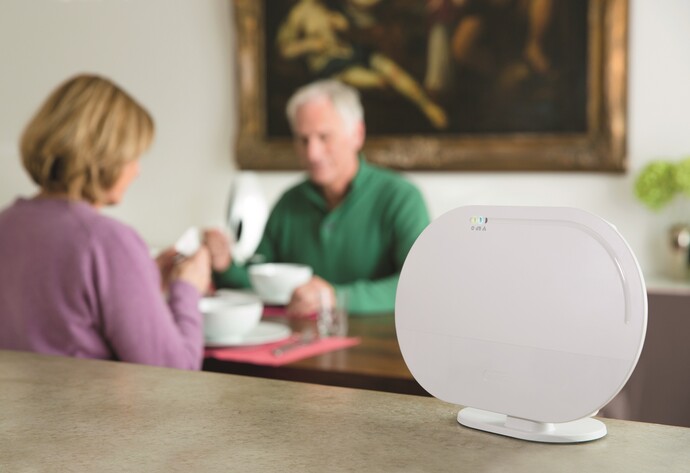 &Auml;lteres Paar sitzt am Tisch und isst, daneben ein Smart Home Controller