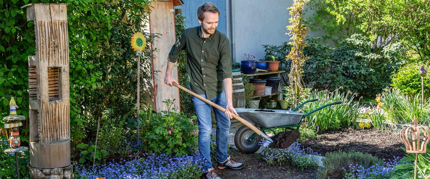 Mann mit Schaufel im Kompost