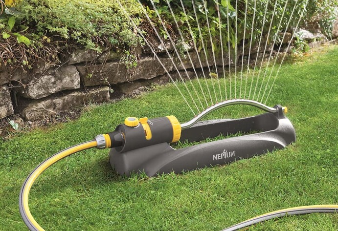 Schwarz-gelber Rasensprenger bew&auml;ssert den Garten