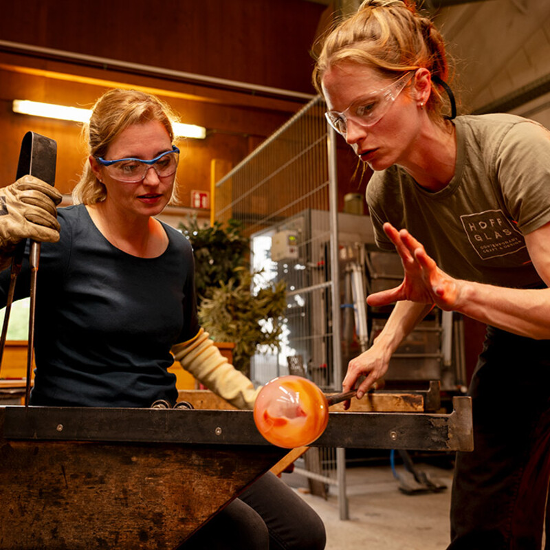 Glasmacherin Pia Hoff zeigt einer Workshop-Teilnehmerin die Kunst der traditionellen Glasfertigung