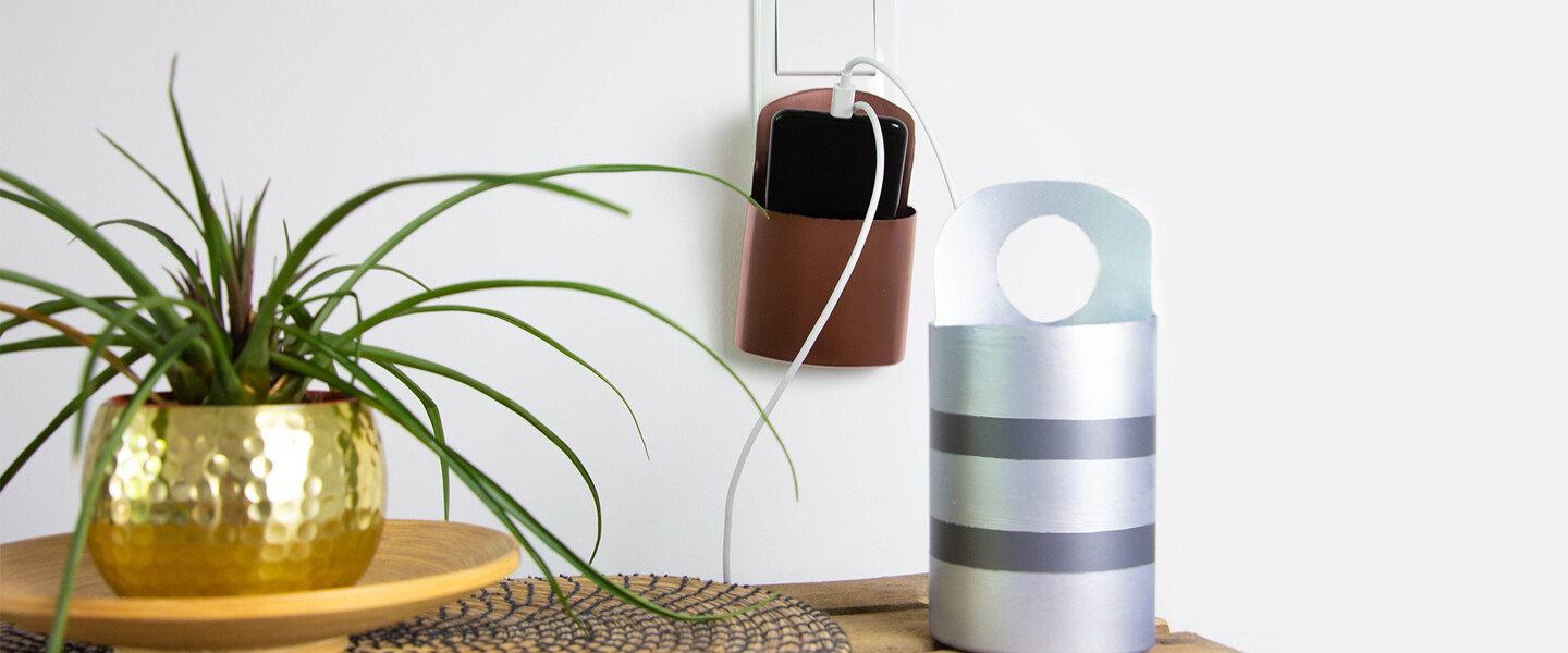 Smartphone in DIY Smartphone-Ladestation an Steckdose hinter Ladestation auf Tisch