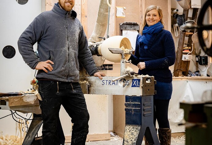Ein Mann und eine Frau stehen in einer Werkstatt neben einer Drechselbank