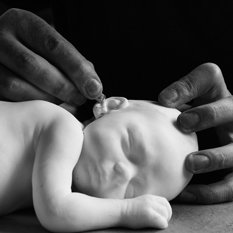 Männerhände bearbeiten filigrane Baby-Skulptur