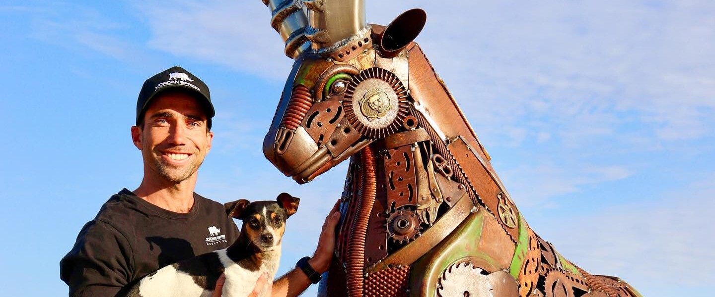 Mann mit Hund neben Metallskulptur