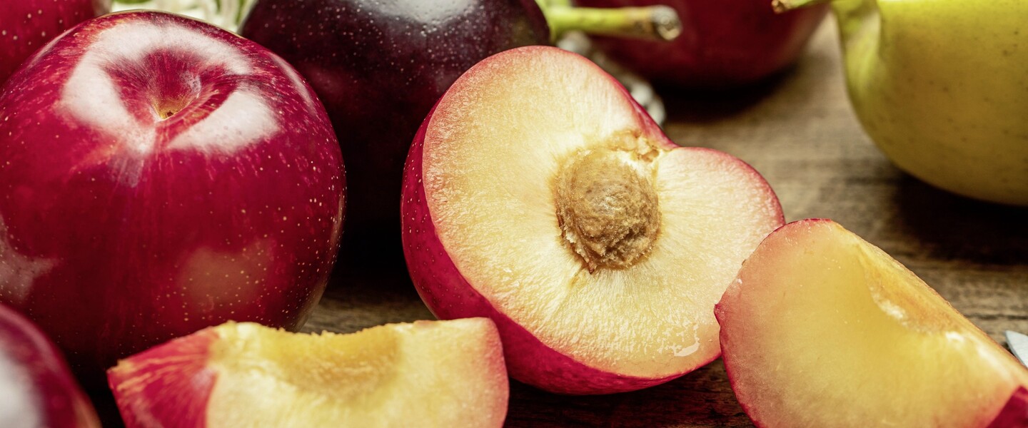 Nektarinen liegen ganz und geschnitten auf Tisch