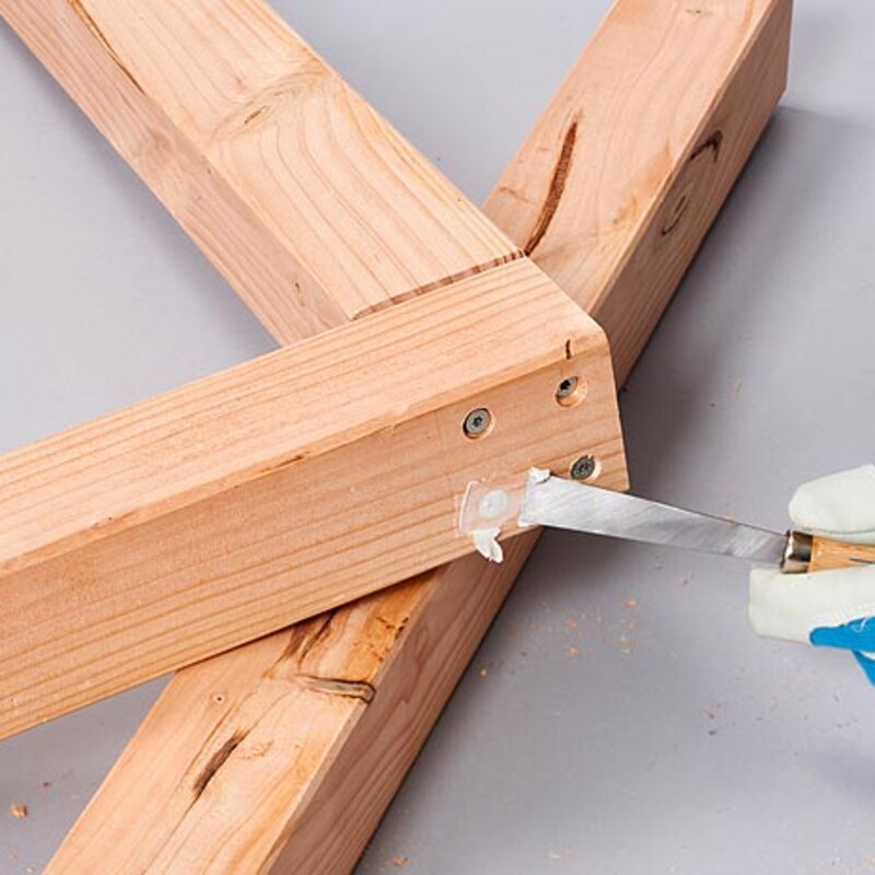 Hand hält Spachtel und spachtelt mit Holzspachtel Vertiefung in Holzrahmen