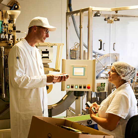 Mitarbeiter von Samen Maier bei der Qualit&auml;tskontrollIm Gespr&auml;ch: Johannes Huber und Mitarbeiterin Rebecca Appelius vor einer Abf&uuml;llmaschine.
