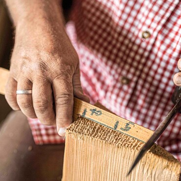 Schindelmacher Ernst Karle pr&uuml;ft das Ma&szlig; eines Holzst&uuml;ckes