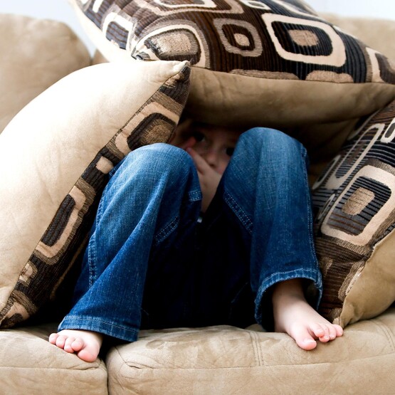 Kind versteckt sich unter Kissen