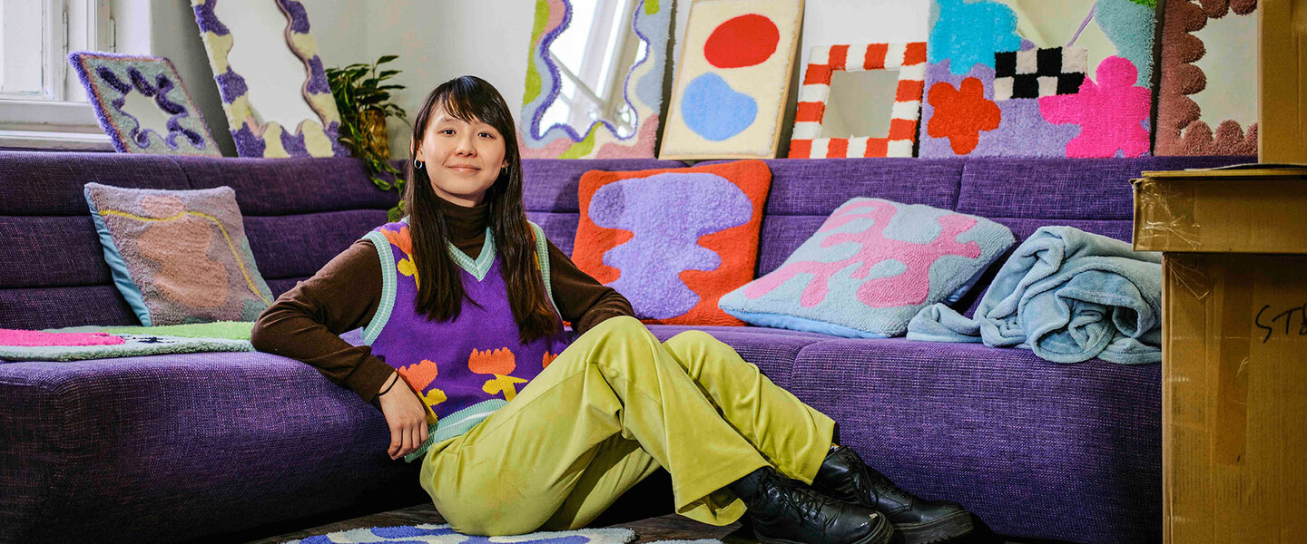 Tufterin Zeyu Cheng sitzt vor Sofa auf Fußboden