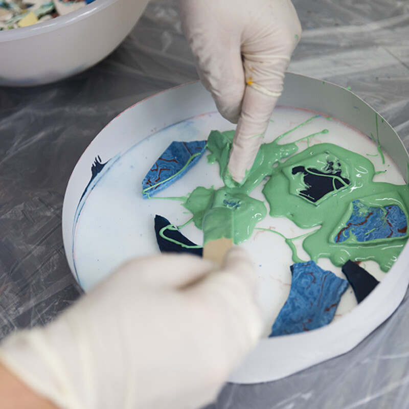 H&auml;nde mit Plastik-Handschuhen kleben Scherbe an Papp-Vorrichtung