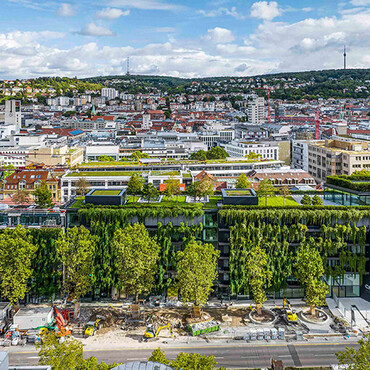 Blick von oben auf die Skyline einer Stadt mit begrünten Gebäude im Vordergrund