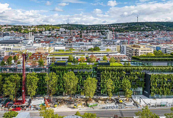 Blick von oben auf die Skyline einer Stadt mit begrünten Gebäude im Vordergrund