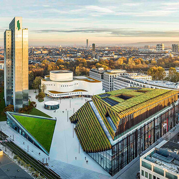 Blick von oben auf die Skyline einer Stadt mit begrünten Gebäude im Vordergrund