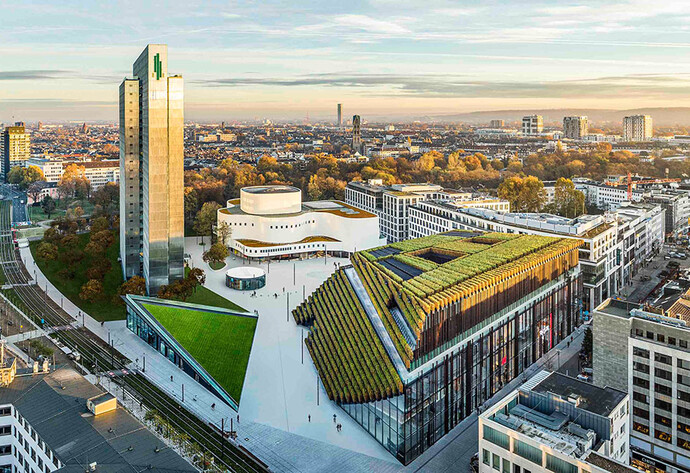 Blick von oben auf die Skyline einer Stadt mit begrünten Gebäude im Vordergrund