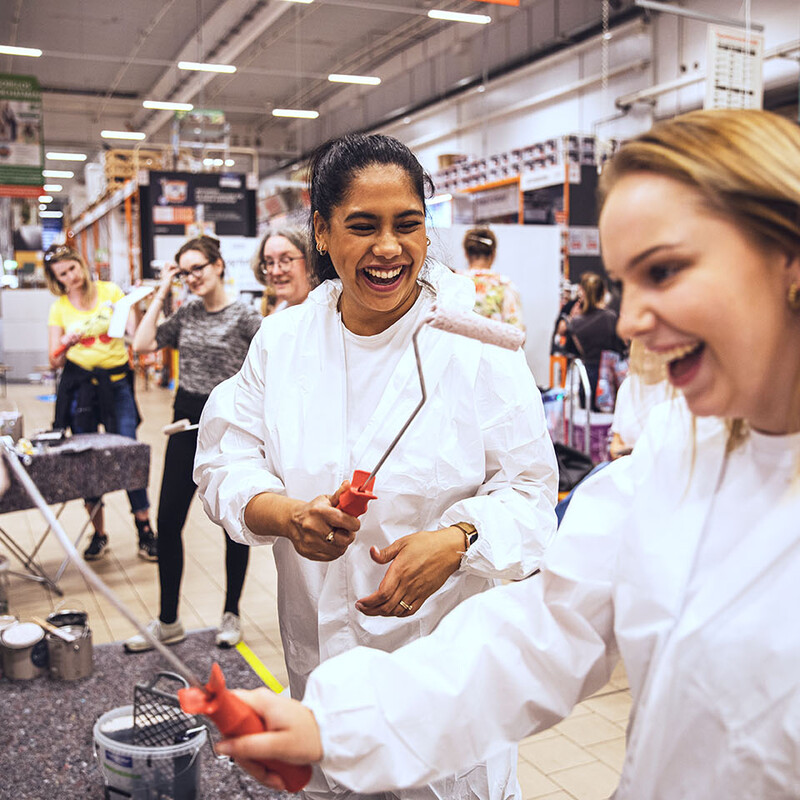 Zwei Frauen mit Farbrolle und weißen Overalls