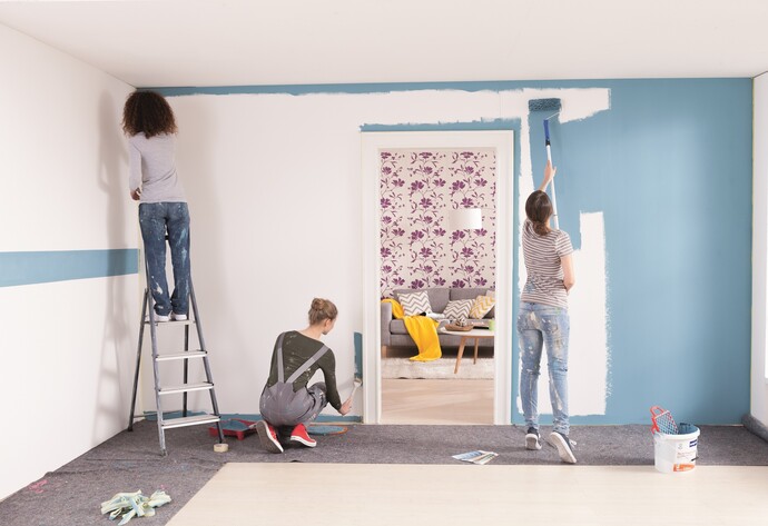 Drei Frauen streichen eine Wand