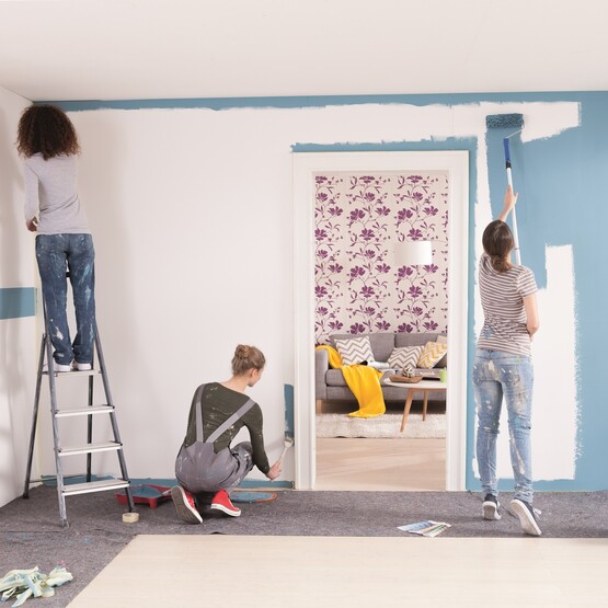 Drei Frauen streichen eine Wand