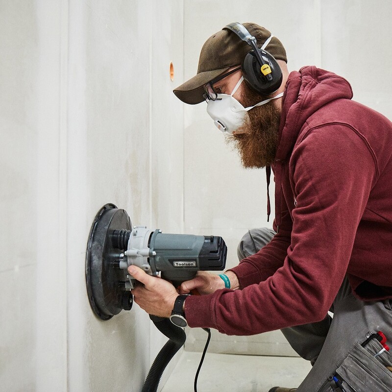 Bauhaus Workshop - Wandverkleidung mit Gipskartonplatten: Verspachtelte Wand wird von Markus abgeschliffen